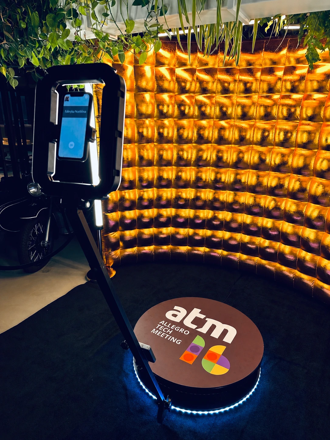 Fotobudka 360 z personalizacją Allegro Tech Meeting na tle złotej ścianki