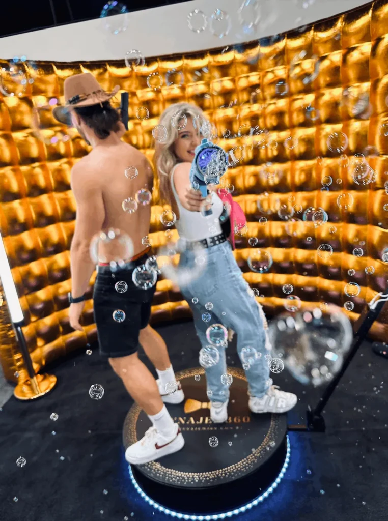 Goście bawiący się na fotobudce 360 z efektem baniek mydlanych podczas eventu.